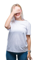 Young blonde woman over isolated background smiling and laughing with hand on face covering eyes for surprise. Blind concept.