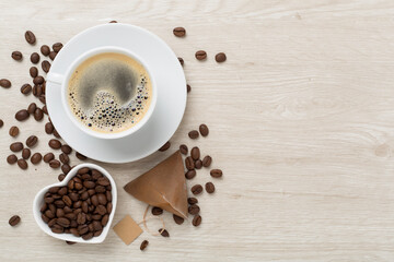Cup of coffee made using pyramid on wooden background, top view