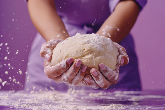 A woman is kneading dough, isolated on a purple background. she testing the dough for baking bread