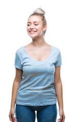 Obraz premium Young blonde woman over isolated background looking away to side with smile on face, natural expression. Laughing confident.