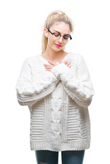 Young beautiful blonde woman wearing glasses over isolated background smiling with hands on chest with closed eyes and grateful gesture on face. Health concept.