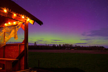 northern lights on a spring night in the middle of a field where there is an outdoor terrace with a...