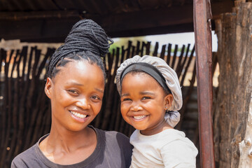 village african mother and baby standing at the entrance of the shack, township village in south...