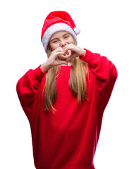 Young beautiful girl wearing christmas hat over isolated background smiling in love showing heart symbol and shape with hands. Romantic concept.