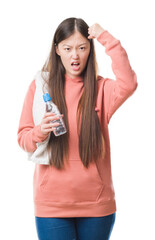 Obraz premium Young Chinese woman over isolated background wearing sport sweathshirt annoyed and frustrated shouting with anger, crazy and yelling with raised hand, anger concept
