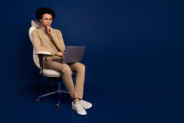 Full body photo of young man sit armchair netbook thoughtful dressed stylish beige clothes isolated...