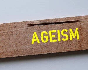 Wood piece with yellow text AGEISM, bias against discrimination or bullying on elderly against...