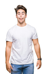 Obraz premium Young handsome man wearing white t-shirt over isolated background making fish face with lips, crazy and comical gesture. Funny expression.