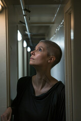 A woman standing in a hallway, gazing upwards in contemplation