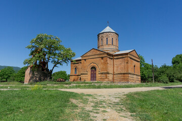 Fototapeta premium Michael Archangel Church and bell tower of Algeti village are built of red brick. Bright blue sky.