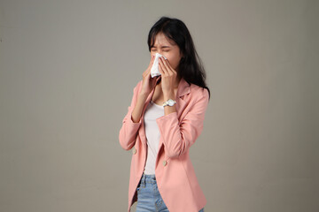 asian woman wearing formal casual sneeze with tissue paper on isolated background. Female blowing...