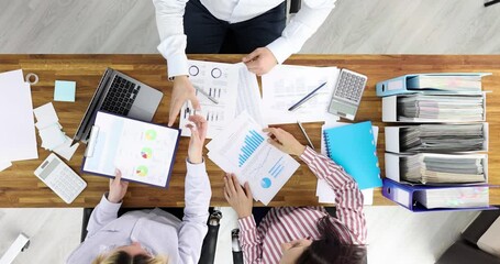 Business partners studying documents with graphs and shaking hands top view 4k movie slow motion. Successful customer service in business concept