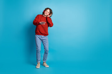 Fototapeta premium Full length photo of funky cool guy dressed red pullover headphones listening melody emtpy space isolated blue color background