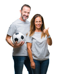 Middle age hispanic couple holding football soccer ball over isolated background pointing and...