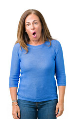 Middle age beautiful woman wearing winter sweater over isolated background In shock face, looking skeptical and sarcastic, surprised with open mouth