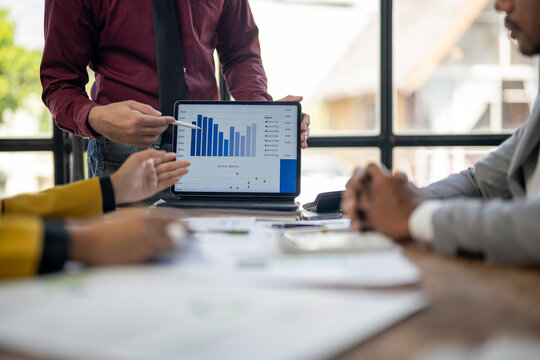A man is showing a graph to a group of people. The graph shows a downward trend, which could indicate a decrease in sales or a decline in performance