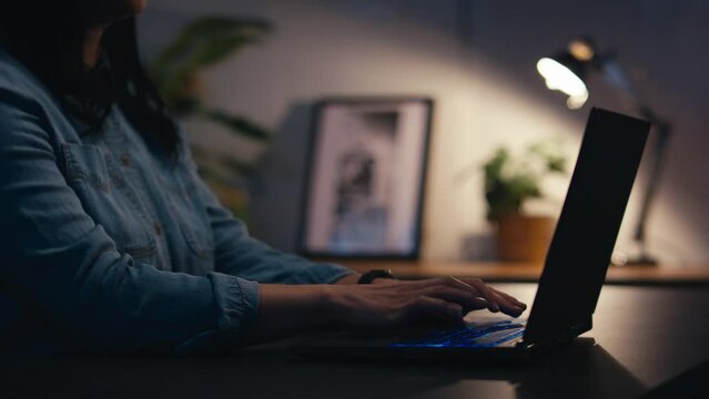 Close up of woman at home interacting with virtual computer screen on laptop using pinch and swipe gestures at night - shot in slow motion