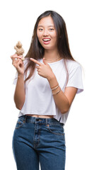 Young asian woman holding fresh organic over isolated background very happy pointing with hand and...