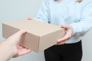 Delivery person with packages, hand holds a box, close up. Woman hand accepting a delivery box