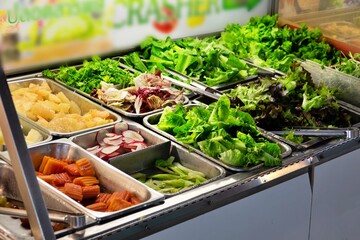 A salad bar with many different types of vegetables, including carrots, broccoli