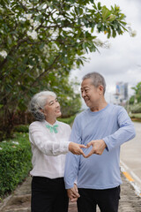 Happy Asian senior couple walking together on a tropical forest path Retired old man and woman...