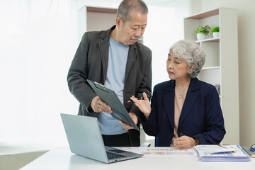 Two senior Asian businessmen analyze finances with documents. Man and woman work on financial...