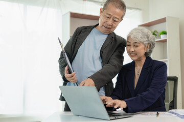 Two senior Asian businessmen analyze finances with documents. Man and woman work on financial...