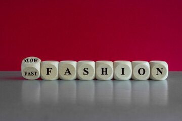 Fast or slow fashion symbol. Cubes form the expression Fast fashion and Slow fashion. Beautiful grey table red background. Business fast or slow fashion concept. Copy space.