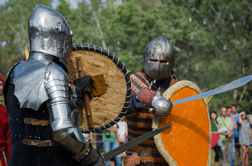 Battle of warriors tournament. Armed members of history club in knight armor demonstrating fighting...