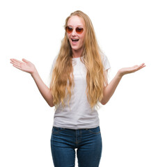 Blonde teenager woman wearing sunglasses very happy and excited, winner expression celebrating...