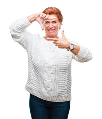 Atrractive senior caucasian redhead woman wearing winter sweater over isolated background smiling making frame with hands and fingers with happy face. Creativity and photography concept.