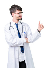 Young doctor man wearing hospital coat over isolated background Looking proud, smiling doing thumbs up gesture to the side