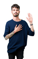 Young handsome man over isolated background Swearing with hand on chest and open palm, making a...