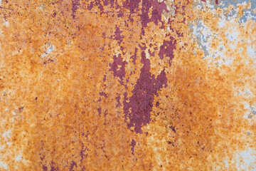 A very old rusty metal surface with peeling paint.
