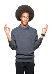 Young african american business man with afro hair relax and smiling with eyes closed doing meditation gesture with fingers. Yoga concept.