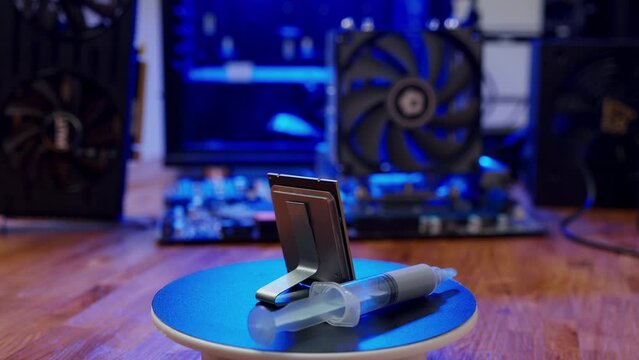 Computer processor with thermal paste rotates close up. Modern computer part with PC case on background. Building personal gaming and workstation pc concept