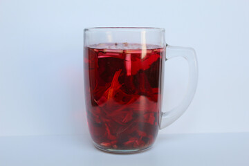 Wedang Uwuh, or traditional tea from brewed sappanwood, ginger, lemongrass and cardamom. In transparent glass, isolated on white background