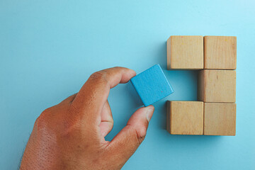  Hand Selects Blue Wooden Cube from Array, Illustrating Decision-making Process idea for...