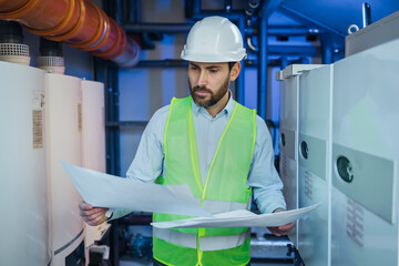 Focused engineer standing near heating system and checking correspondence of data with construction...