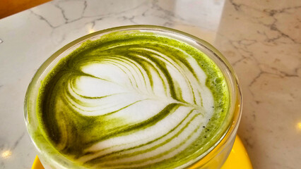 Close-up of a beautifully crafted matcha latte, featuring a swirl of creamy foam on top
