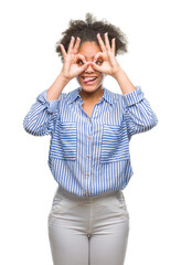 Young afro american woman over isolated background doing ok gesture like binoculars sticking tongue out, eyes looking through fingers. Crazy expression.