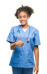 Young afro american doctor woman over isolated background doing happy thumbs up gesture with hand. Approving expression looking at the camera with showing success.