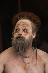 Portrait of an holy male naga sadhu baba with ash on his and long hairs wearning rudraksha necklace...