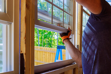 An installation of plastic windows in new home is performed by construction worker