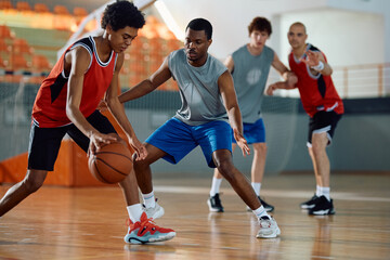 Black defense player trying to block his opponent during basketball match.