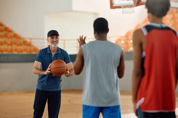 Happy basketball coach and his players during sports training on court.
