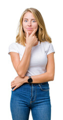 Fototapeta premium Beautiful young woman wearing casual white t-shirt over isolated background looking confident at the camera with smile with crossed arms and hand raised on chin. Thinking positive.