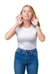 Beautiful young woman wearing casual white t-shirt over isolated background Trying to hear both hands on ear gesture, curious for gossip. Hearing problem, deaf