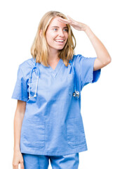 Beautiful young doctor woman wearing medical uniform over isolated background very happy and smiling looking far away with hand over head. Searching concept.