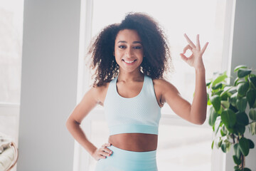 Portrait of pretty sportive young girl demonstrate okey symbol sportswear morning workout apartment...